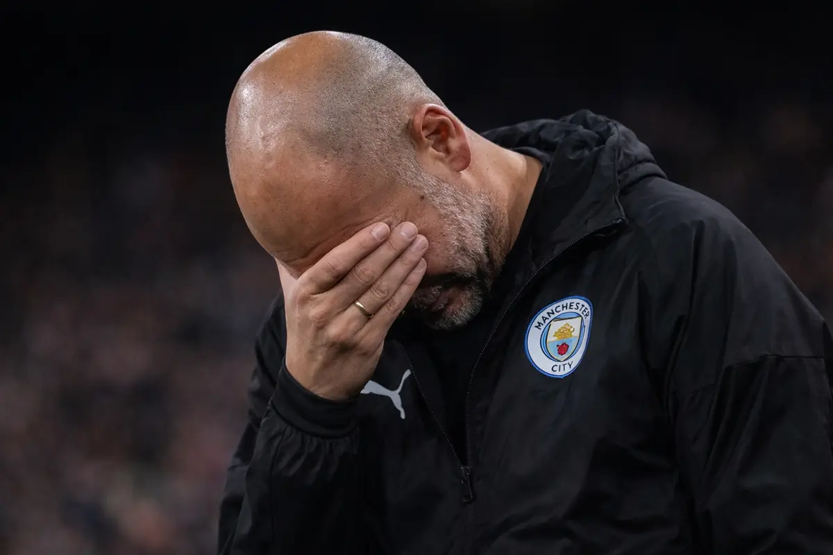 Guardiola con la testa bassa e la mano sul viso